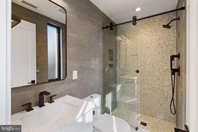 full bath with tile walls, visible vents, toilet, a shower stall, and vanity