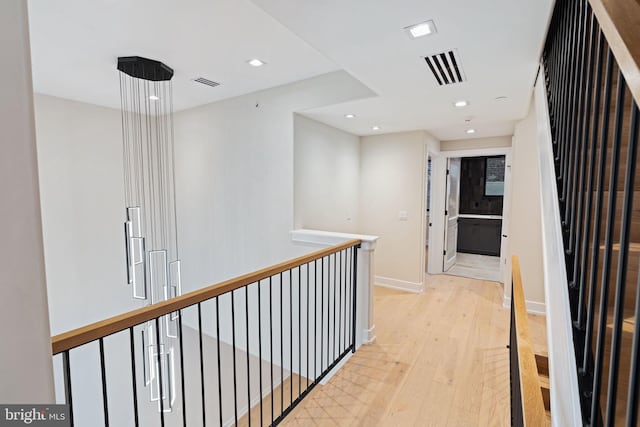 corridor featuring visible vents, an upstairs landing, light wood-style flooring, and baseboards