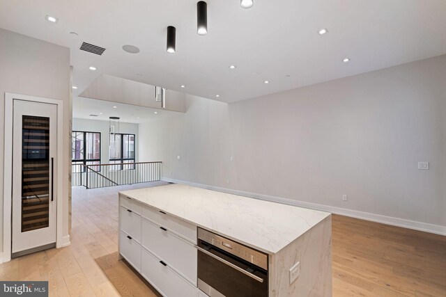 kitchen with light wood-type flooring, a center island, tasteful backsplash, white cabinets, and hanging light fixtures