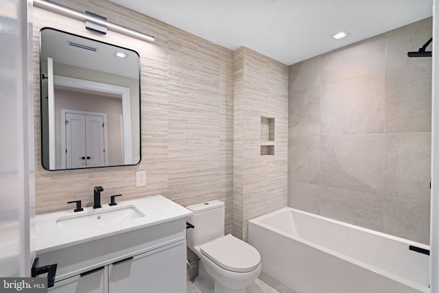 full bath with toilet, bathing tub / shower combination, tile walls, and vanity