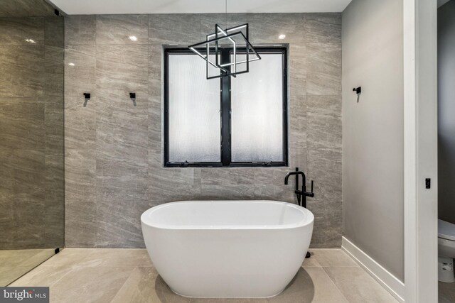 bathroom with a bathing tub, tile patterned flooring, and tile walls