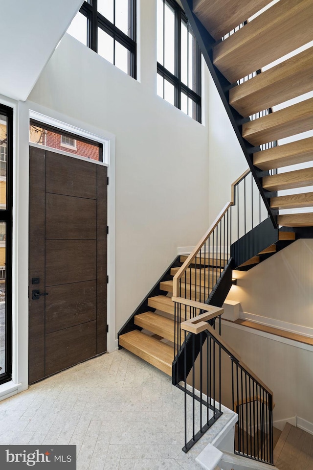 entrance foyer featuring a high ceiling, stairway, and light wood-style floors