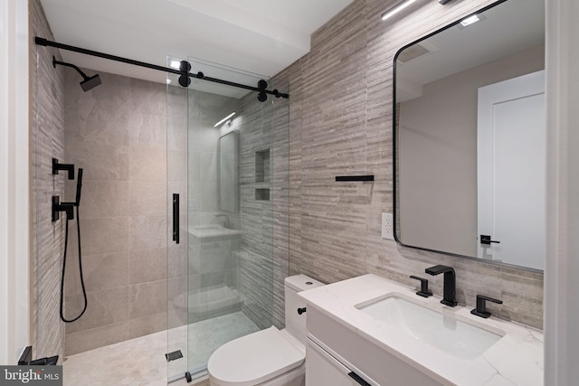 bathroom featuring tile walls, decorative backsplash, toilet, a stall shower, and vanity