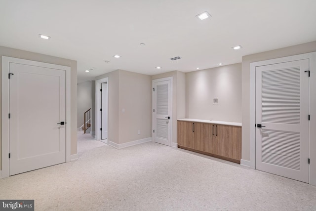 unfurnished room with baseboards, visible vents, stairway, and recessed lighting