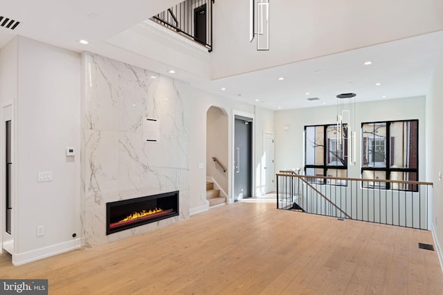 unfurnished living room featuring a high end fireplace, light wood-type flooring, visible vents, and recessed lighting