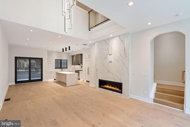 unfurnished living room featuring recessed lighting, a fireplace, visible vents, stairway, and light wood finished floors