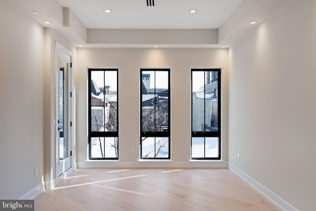 doorway featuring light wood finished floors, baseboards, and recessed lighting