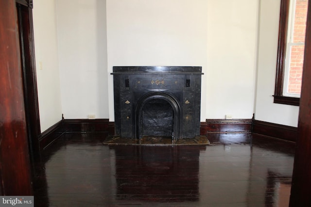 interior details with baseboards, a tiled fireplace, and wood finished floors