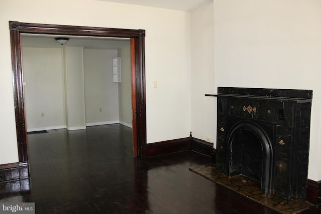 washroom with dark wood-style flooring, a fireplace with raised hearth, and baseboards