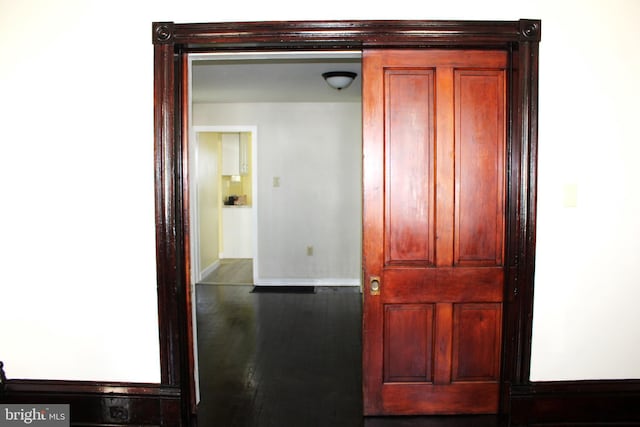 hall with baseboards and wood finished floors