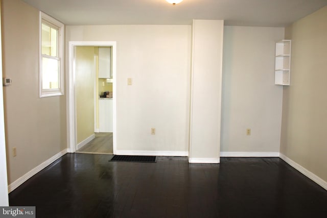 unfurnished room featuring dark wood-style flooring and baseboards