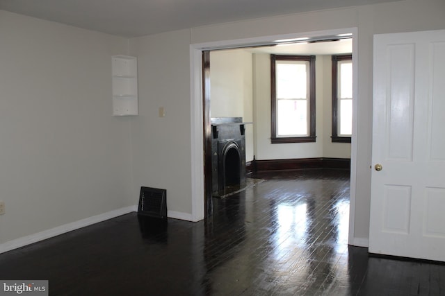 clothes washing area with washer / clothes dryer, dark wood-style flooring, a fireplace with flush hearth, and baseboards