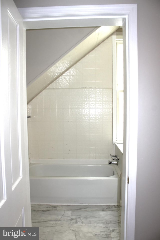 bathroom featuring marble finish floor and a bathing tub