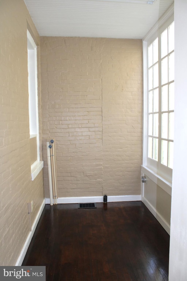 spare room with brick wall, visible vents, and a wealth of natural light