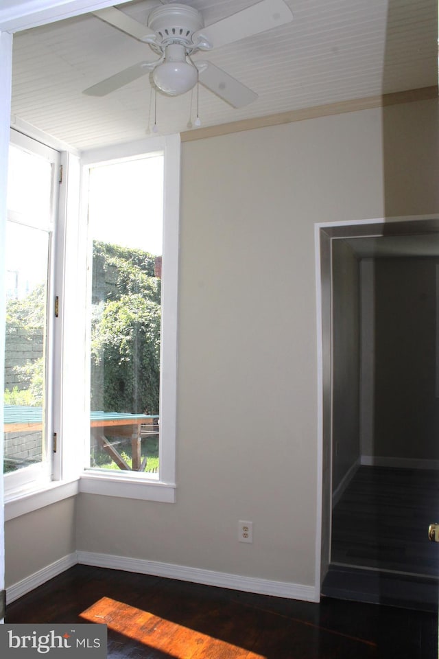 unfurnished room with wood finished floors, a ceiling fan, and baseboards