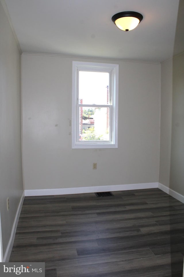 spare room with ornamental molding, visible vents, dark wood finished floors, and baseboards