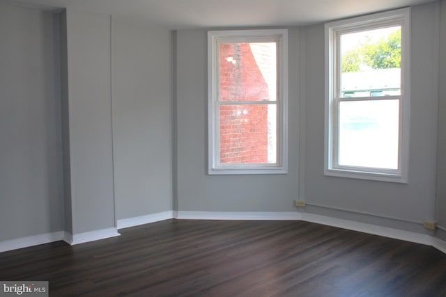 unfurnished room with dark wood-style flooring and baseboards