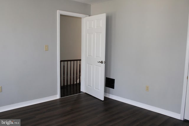 unfurnished room with dark wood finished floors and baseboards