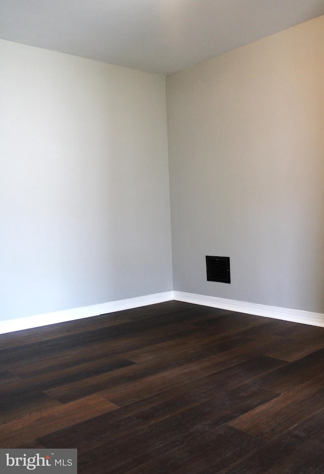 spare room with dark wood-style floors, baseboards, and visible vents