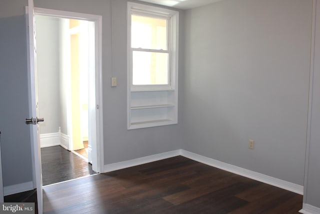 unfurnished room with dark wood finished floors and baseboards