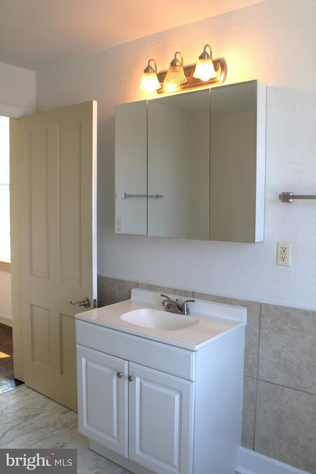 bathroom featuring a textured wall, marble finish floor, and vanity