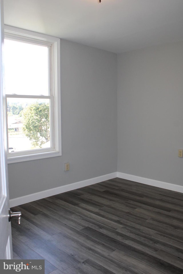 spare room featuring dark wood finished floors and baseboards