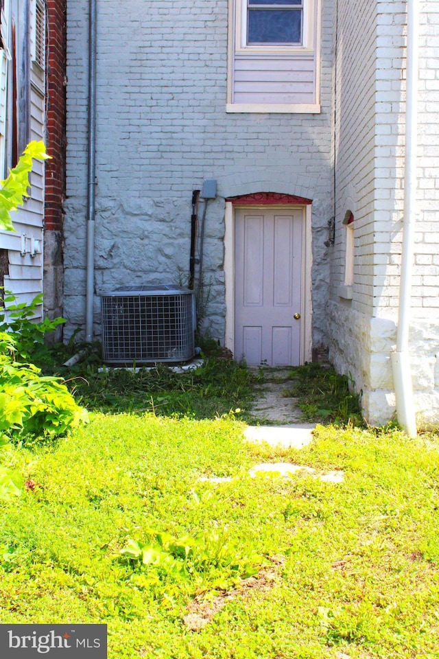 property entrance with cooling unit and brick siding