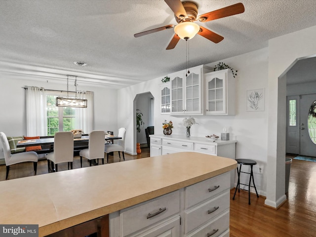 kitchen featuring a textured ceiling, ceiling fan, white cabinetry, and dark hardwood / wood-style flooring