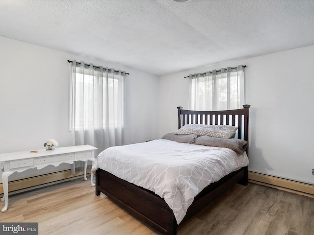 bedroom with a baseboard radiator, light hardwood / wood-style flooring, and a textured ceiling