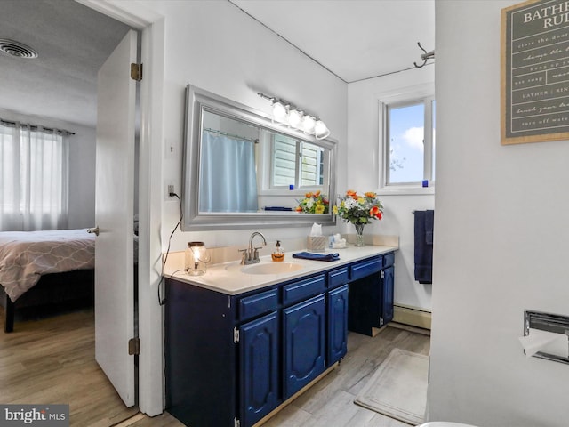 bathroom with a textured ceiling, vanity, wood-type flooring, and baseboard heating