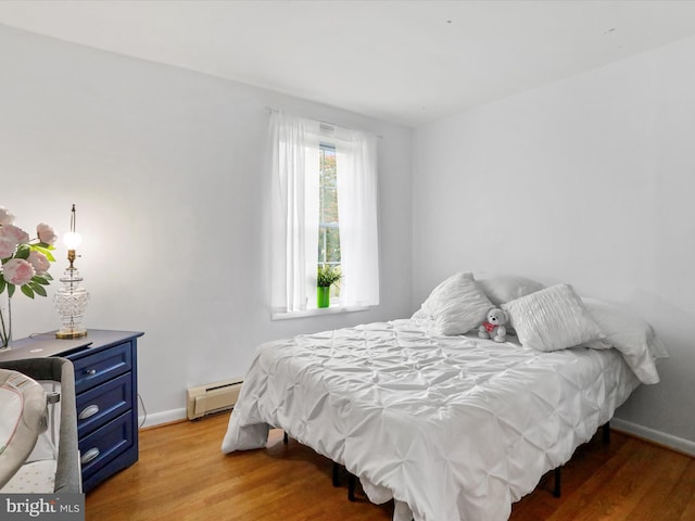 bedroom with wood-type flooring and baseboard heating