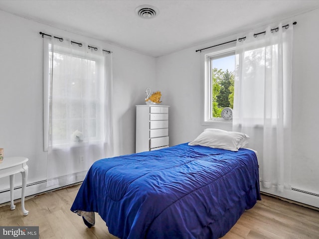 bedroom with light wood-type flooring and baseboard heating