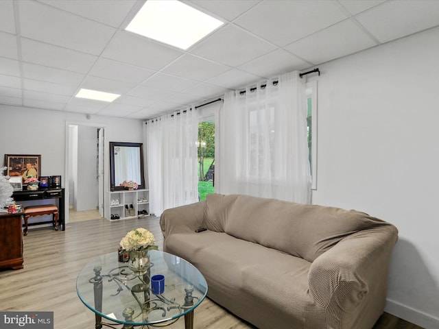 living room featuring light wood-type flooring and a paneled ceiling