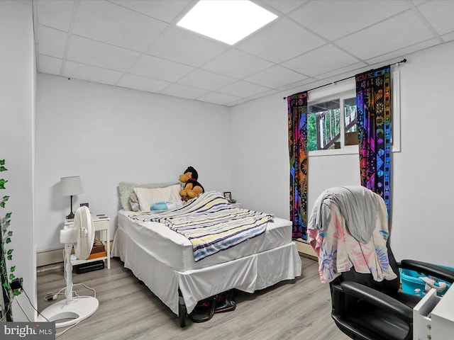 bedroom with a drop ceiling and hardwood / wood-style floors