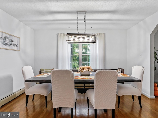 dining area with a textured ceiling, a baseboard radiator, and hardwood / wood-style floors