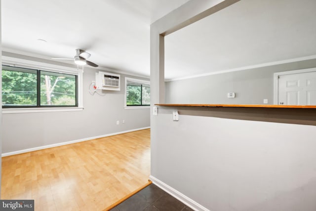 interior space with ceiling fan, ornamental molding, a wall unit AC, and hardwood / wood-style flooring