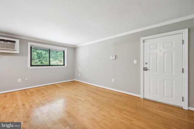 interior space featuring ornamental molding, a wall mounted air conditioner, light wood-style flooring, and baseboards