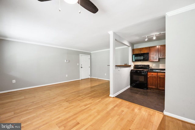 kitchen with baseboards, black appliances, wood finished floors, and crown molding