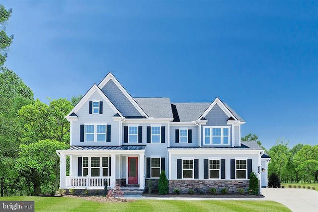 craftsman-style home featuring driveway, stone siding, metal roof, a standing seam roof, and covered porch