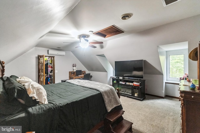 carpeted bedroom with visible vents, attic access, a ceiling fan, vaulted ceiling, and a wall mounted air conditioner