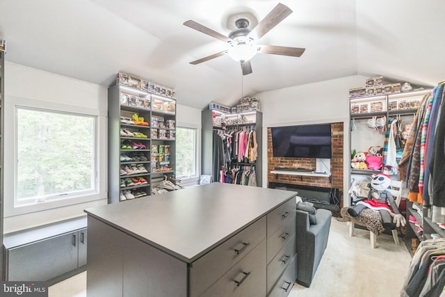 walk in closet with a ceiling fan, light carpet, and vaulted ceiling