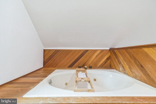 bathroom with a tub with jets and wood walls