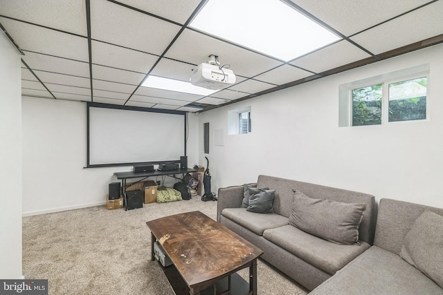 carpeted home theater with a paneled ceiling and baseboards