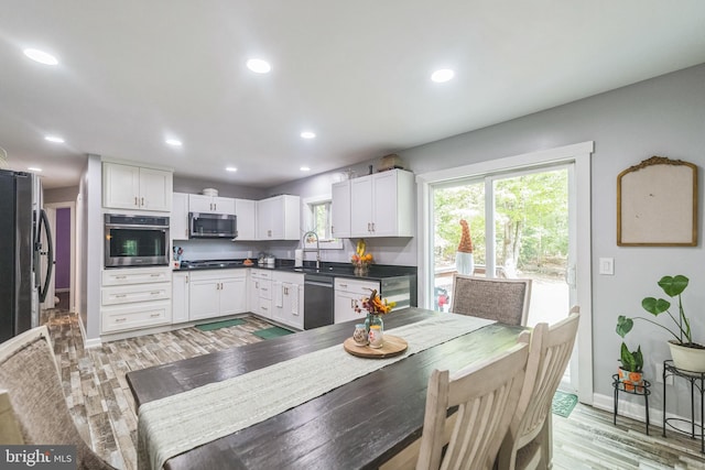 kitchen with appliances with stainless steel finishes, dark countertops, a wealth of natural light, and white cabinetry