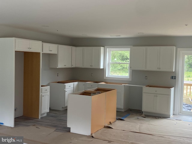 kitchen featuring white cabinets, a kitchen island, light wood-type flooring, and a healthy amount of sunlight