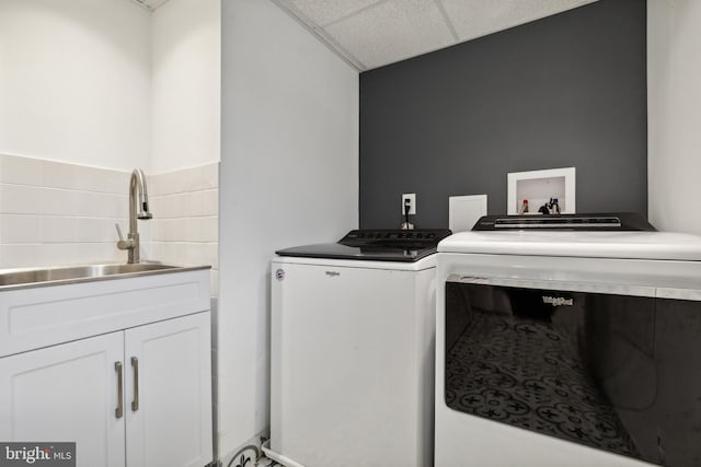 washroom featuring cabinets, sink, and washing machine and dryer