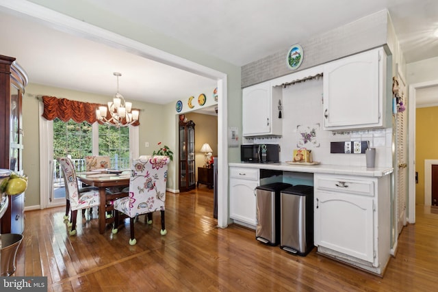 kitchen with decorative light fixtures, hardwood / wood-style floors, a notable chandelier, and white cabinetry