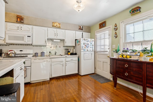 kitchen featuring hardwood / wood-style floors, white appliances, white cabinetry, sink, and tasteful backsplash