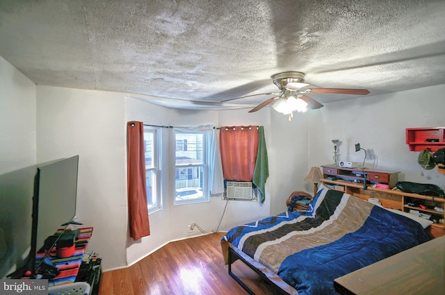 bedroom featuring ceiling fan, wood-type flooring, a textured ceiling, and cooling unit