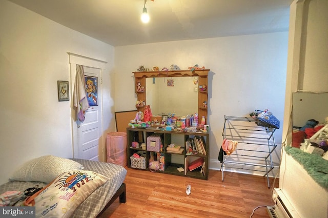 bedroom with a baseboard radiator and wood finished floors